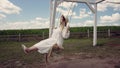 Young woman in a stylish summer oufit sitting on a swing