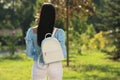 Young woman with stylish white backpack in park, back view. Space for text