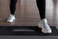 Young woman in stylish white sneakers in black leggings does exercises on the steps of the platform in the gym. Royalty Free Stock Photo