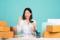 Young woman successful wear casual shirt sit work at white office desk with laptop and cardboard box. She hold credit bank card do Royalty Free Stock Photo