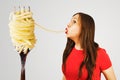 Young woman sucks huge spaghetti from a huge fork