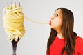 Young woman sucks huge spaghetti from a huge fork