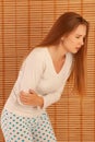 Young woman suffering from abdominal pain while sitting on bed at home Royalty Free Stock Photo