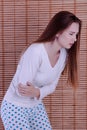 Young woman suffering from abdominal pain while sitting on bed at home Royalty Free Stock Photo