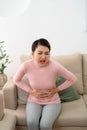 Young woman suffering from abdominal pain while sitting on sofa at home Royalty Free Stock Photo