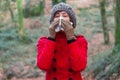 Young woman suffering from cold or flu blowing nose or sneezing on white paper handkerchief Royalty Free Stock Photo