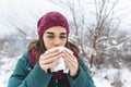 Young woman suffering from a seasonal cold and flu blowing her nose on a handkerchief as she stands outdoors on winter. Healthcare Royalty Free Stock Photo