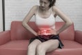 Young woman suffering from strong abdominal pain while sitting on sofa at home Royalty Free Stock Photo