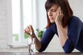 Young woman suffering from strong headache, holding fingers to her temples and closing eyes from pain, prepairing to take medicine