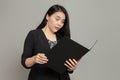 Young woman in suit with dumbfounded expression while holding and looking at folder