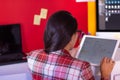 A young woman in suit using a tablet in a colorful office