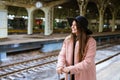 Young woman with suitcase on platform of station. Traveler girl waiting Royalty Free Stock Photo