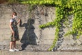 Young woman in summer dress and protective face mask alone stands next to concrete wall with ivy Royalty Free Stock Photo