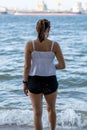 Young woman in summer white shirt standing on beach and looking to the sea. Asian girl relaxing and enjoying peace on vacation Royalty Free Stock Photo