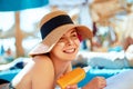 Young woman with sun cream on face holding sunscreen bottle on the beach. Royalty Free Stock Photo