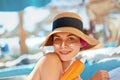 Young woman with sun cream on face holding sunscreen bottle on the beach. Female in hat applying moisturizing lotion on skin Royalty Free Stock Photo