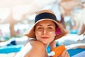 Young woman with sun cream on face holding sunscren bottle on the beach.