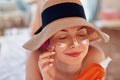 Young woman with sun cream on face holding sunscren bottle on the beach. Royalty Free Stock Photo