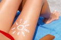 Young woman with sun shape on the leg holding sun cream bottle on the beach. Sun protection sun cream, on her smooth tanned legs.S Royalty Free Stock Photo