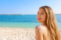 Young woman with sun shape on the shoulder. Beautiful happy cute woman applying suntan cream on her shoulder with beach background Royalty Free Stock Photo