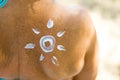 Young woman with sun shaped suntan lotion on her back at the beach. Girl shoulder applying protection cream before Royalty Free Stock Photo