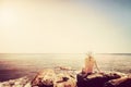Young woman sunbathing on rocky beach. Vintage Royalty Free Stock Photo