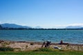 A young woman is sunbathing on a wild beach against the background of mountains. There is a bicycle next to her