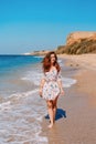 Young woman in sunglasses and dress on the beach in front of the sea