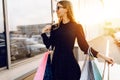 Young woman in sunglasses and dress, with shopping bags, in the city against the background of a shopping center Royalty Free Stock Photo