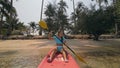 Young woman in sunglasses pulls pink plastic canoe with paddle to azure sea water from beach with palms. Royalty Free Stock Photo