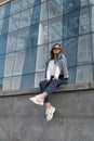 Young woman in sunglesses in youth clothing on the city street. Attractive stylish woman resting on city street.Vertical Royalty Free Stock Photo