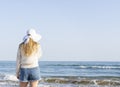 Young woman in sunhat standing on the beach,enjoying and looking at the ocean.Outdoor summer vacation lifestyle concept.Travel and