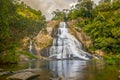 Young woman in a Sunny day in the Tropical waterfall falls from the mountain cliff to the jungle, serene landscape of Diyaluma fal Royalty Free Stock Photo