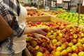 Young woman in a supermarket. Woman holding red apples while choosing fresh fruits and vegetables at farmers market, copy space. Royalty Free Stock Photo