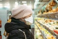 Young woman in supermarket in medical mask chooses fruits and other food. Coronavirus pandemic Covid-19 virus