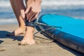 Young woman surfer getting on the surfboard`s leash