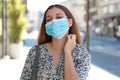 Young woman with surgical mask itching allergy symptoms scratching neck in city street