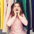 Young woman surprised in shop. Sale, gifts, holidays and people concept. Amazed woman sitting among clothes in wardrobe. Emotional