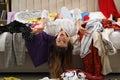 Young woman surrounded by different clothes in messy room. Fast fashion concept