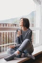 Young woman in a sweater and boyfriend jeans relaxing near big window Royalty Free Stock Photo