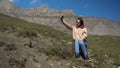 A young woman in a sweatshirt sits in the mountains and takes a selfie on a smartphone. Royalty Free Stock Photo