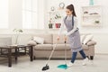Young woman sweeping house with broom and scoop