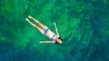 Young woman swimming in blue sea lagoon in crystal clear water, girl in bikini swims and relax, aerial view from above Royalty Free Stock Photo