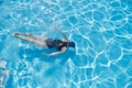 Young woman swimming underwater in an outdoor pool, top view of back of girl Royalty Free Stock Photo