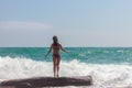 A young woman in a swimsuit, looking at the beautiful waves of the ocean. Rest near the sea. The sea season