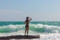 A young woman in a swimsuit, looking at the beautiful waves of the ocean. Rest near the sea. The sea season