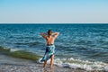 Young woman in a swimsuit and pareo stands against the background of the sea horizon - view from the back. A slender adult girl Royalty Free Stock Photo