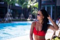 Young woman in swimsuit sit on chaise-longue poolside wearing sunglasses Royalty Free Stock Photo