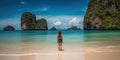 Young woman in swimsuit walking on the beach in Thailand.