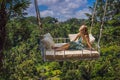 Young woman swinging in the jungle rainforest of Bali island, Indonesia. Swing in the tropics. Swings - trend of Bali